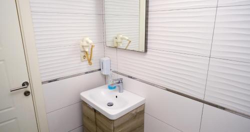 Taksim Next Hotel في إسطنبول: حمام أبيض مع حوض ومرآة