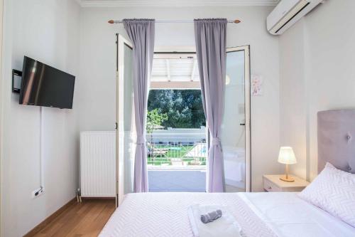 a bedroom with a bed and a large window at Villa Loukiana in Kavos