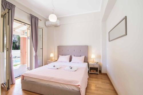 a white bedroom with a bed and a large window at Villa Loukiana in Kavos