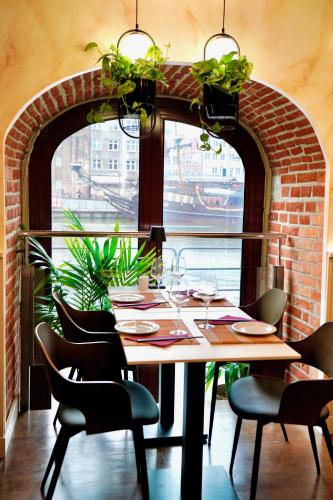 a dining room with a table and chairs and a brick wall at Jess Krolewski Gdansk Old Town in Gdańsk