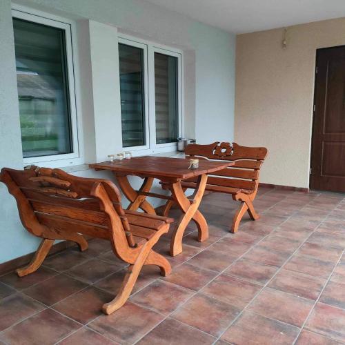 drewniany stół i ławki w pokoju z oknami w obiekcie Pokoje noclegowe w mieście Grajewo