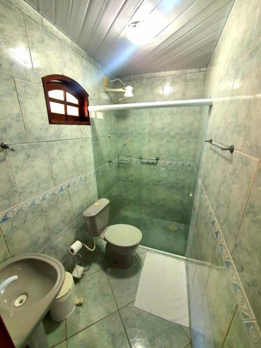 a bathroom with a shower and a toilet and a sink at Pousada Tuiuiu in Angra dos Reis