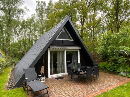 una casa triangular negra con mesa y sillas en Ferienhaus Seehütte en Malschwitz