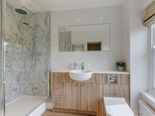 a bathroom with a sink and a mirror and a shower at 3 Bed in Saffron Walden 85662 in Finchingfield