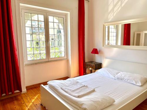 Un dormitorio con una cama blanca con cortinas rojas y una ventana en With Terrasse - 3 Bedroom, 3 Bathroom Triplex, en Lisboa