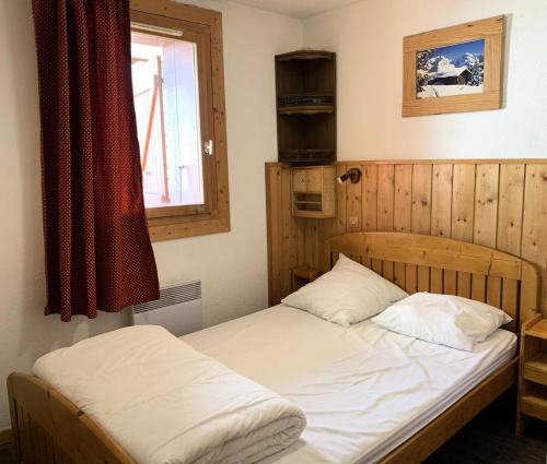 a bedroom with a bed with white sheets and a window at Résidence Courmayeur - 2 Pièces pour 6 Personnes 874 in Les Menuires
