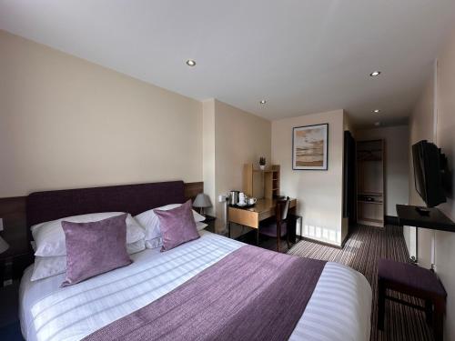 1 dormitorio con 1 cama grande con almohadas moradas en The Bell Guesthouse, en Peterlee