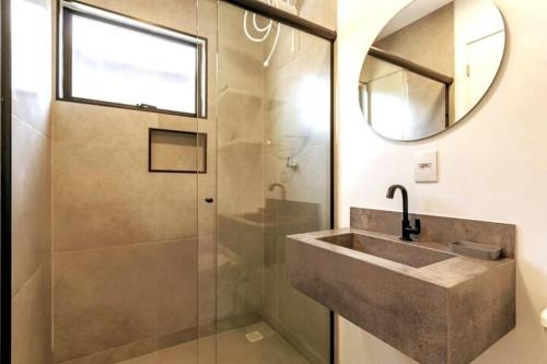 a bathroom with a sink and a shower with a mirror at *A/C*1000Mbps*Cozinha Completa*Estacionamento* in Florianópolis