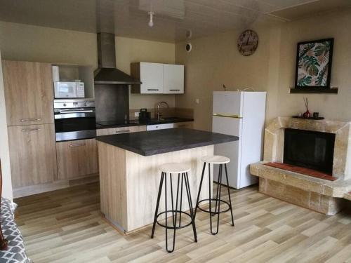 une cuisine avec un comptoir et des tabourets dans une pièce dans l'établissement maison les vieilles cours, à Blosville