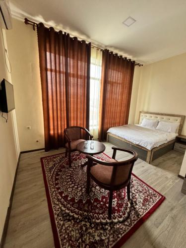 sypialnia z łóżkiem, stołem i krzesłami w obiekcie Rudaki Hotel in Panjakent w mieście Panjakent
