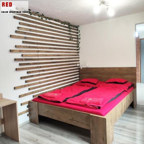 a bed in a room with a wooden wall at Color Apartmanok Eger in Eger