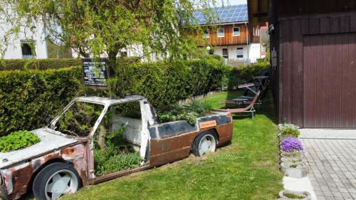 an old car with plants in the back yard at AMW Ferienwohnungen in Legau