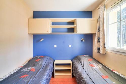 - 2 lits dans une petite chambre aux murs bleus dans l'établissement Résidence Lacanau Les Pins - maeva Home - Appartement 2 pièces 4 personnes - Sélection MAE-5031, à Lacanau