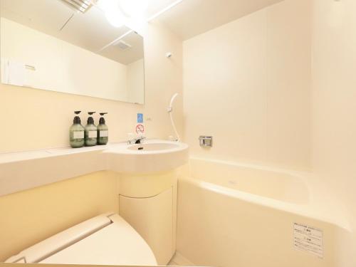 Centurion Hotel Hamamatsu في هاماماتسو: حمام أبيض مع حوض ومرحاض