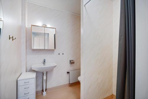 a white bathroom with a sink and a mirror at Lägenhet med trädgård nära stad och hav in Varberg