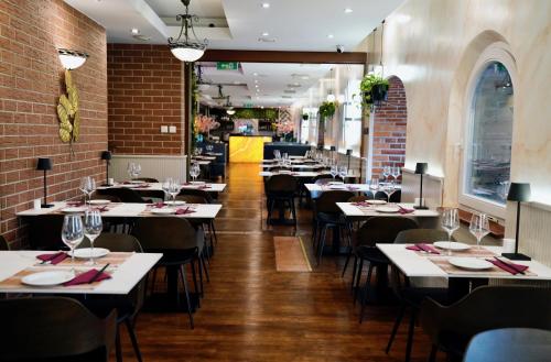 a restaurant with white tables and chairs and brick walls at Jess Krolewski Gdansk Old Town in Gdańsk