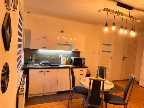 a kitchen with white cabinets and a table with chairs at Villa na Dolnej in Karpacz