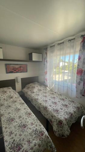 une chambre avec deux lits et une fenêtre dans l'établissement Mobil-home SUNSEA Camping DEL MAR, à Argelès-sur-Mer