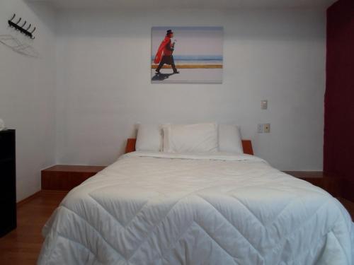 a white bed in a room with a picture on the wall at Hotel María Bonita in Tlaxcala de Xicohténcatl