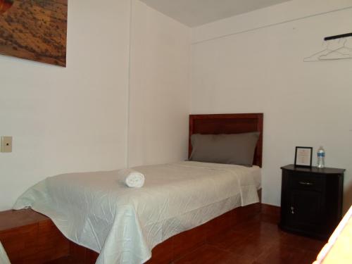 a small bedroom with a bed and a night stand at Hotel María Bonita in Tlaxcala de Xicohténcatl