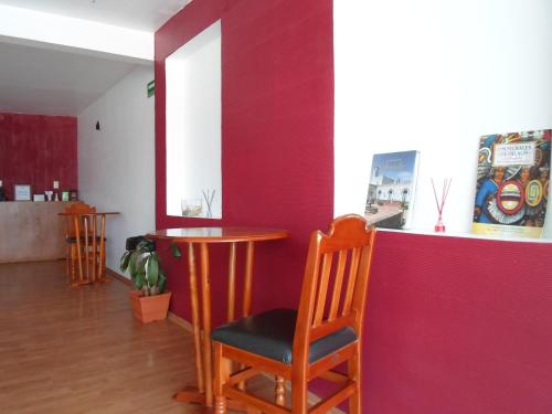 a table and chairs in a room with a red wall at Hotel María Bonita in Tlaxcala de Xicohténcatl
