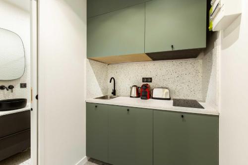 a kitchen with green cabinets and a sink at Chic Apartment in the Prestigious Saint Honoré in Paris