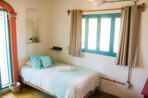 a bedroom with a bed with blue pillows and a window at Sayulita Central Hotel in Sayulita