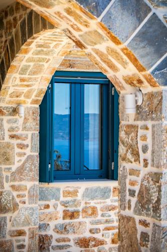 a window in a stone wall with a blue door at RODON Luxury Villas in Skopelos Town