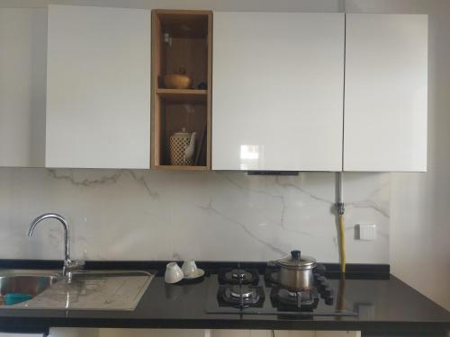 La cuisine est équipée de placards blancs, d'une cuisinière et d'un évier. dans l'établissement Majesty home, à La Marsa