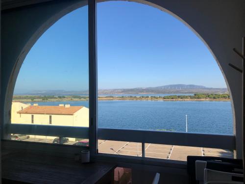 une fenêtre cintrée avec vue sur une étendue d'eau dans l'établissement Studio face à l'étang pour 5 Voyageurs Port-Leucate, à Leucate