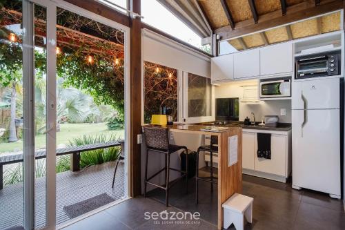 a kitchen with white appliances and a large window at VGZ - Cabanas charmosas entre Barra de Ibiraquera e Rosa in Imbituba