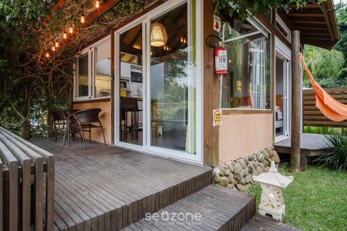 a porch of a house with a table and chairs at VGZ - Cabanas charmosas entre Barra de Ibiraquera e Rosa in Imbituba