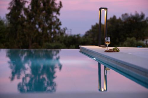 a glass of wine sitting on the edge of a swimming pool at Reveli Suites in Katelios
