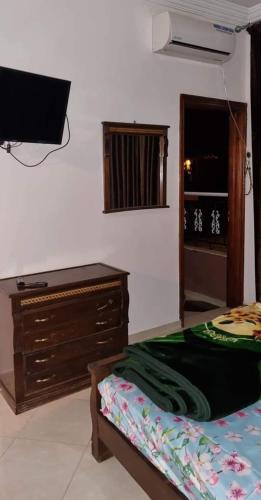 a bedroom with a bed and a dresser and a television at تجزئة القلم حي أطلس بني ملال in Mrhila