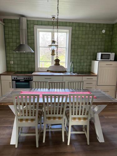 a kitchen with a table and chairs and a kitchen with green tiles at SwedishCountryLiving / Skippers cottage in Köpmannebro