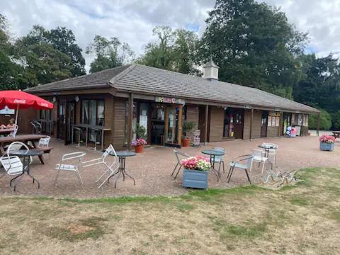 a building with tables and chairs in front of it at Lakeside Escape Modern 2 Bedroom Holiday Home in Overstone