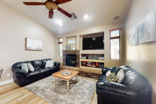a living room with black leather furniture and a flat screen tv at The Beach House in Surprise
