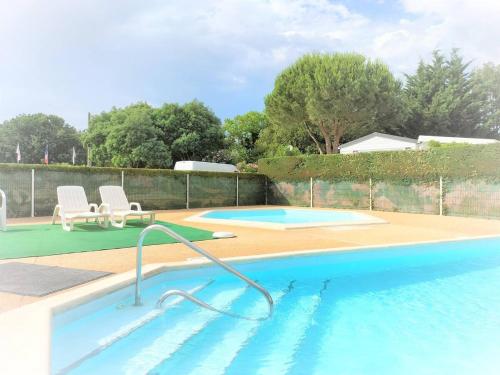 a large swimming pool with two chairs next to it at Mobilhome Domaine des pins à Marennes plage in Marennes