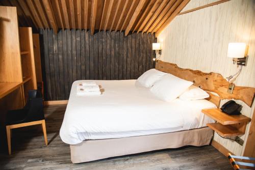 a bedroom with a large bed with white sheets at Alto Melimoyu Hotel & Patagonia in La Junta