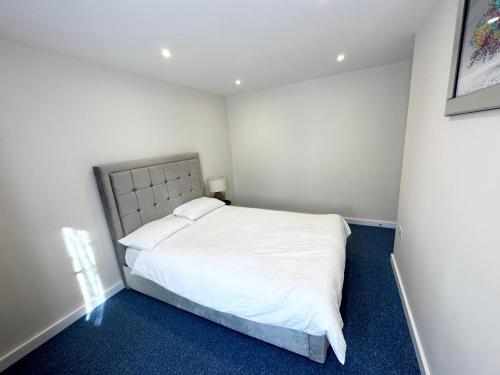 um quarto com uma cama branca e alcatifa azul em 3 Bedroom Home In London - Lee - By Atleys Homes em Londres