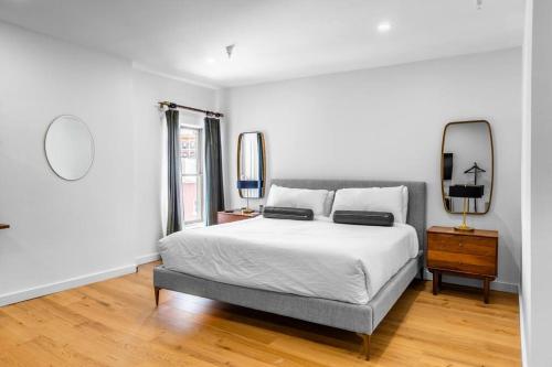 a white bedroom with a bed and a mirror at DTWN Bangor, Historic Hotel, KING BED, WIFI, Roku TV, Room # 403 in Bangor