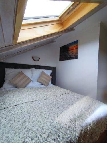 a bedroom with a bed with a skylight at Miły Domek Sasino in Sasino