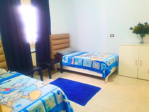 een slaapkamer met 2 bedden, een stoel en een tafel bij Duplex Familial 2 Chambres 131m2 avec Jardin Privé - Service Aéroport - Internet Fibre Optique in Borj Turki