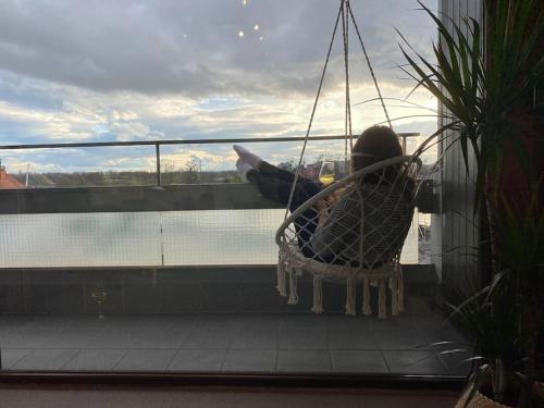 a person sitting in a chair on a balcony at Ferienwohnung Rheinblick in Kehl am Rhein