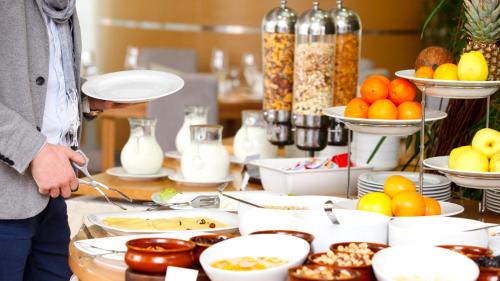 a man standing in front of a table with food at Hotel - Pension Vesta in Bad Elster