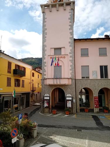 a building with a clock tower in a town at Monolocale in Piazzetta in Torre Pellice