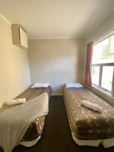 two beds in a small room with a window at Sea View Motel - Unit 7 in Kaikoura