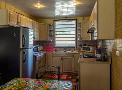 eine Küche mit einem Kühlschrank und einem Tisch darin in der Unterkunft TAHITI - Bungalow Taharuu Surf Hoe in Papara
