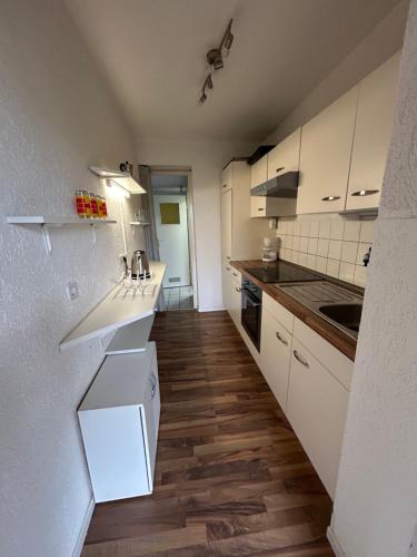 a small kitchen with white cabinets and wooden floors at Am Fuldaufer in Kassel