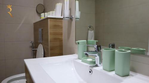 La salle de bains est pourvue d'un lavabo avec des tasses vertes. dans l'établissement Luxury Duplex 2BR Oasis., à Abu Dhabi
